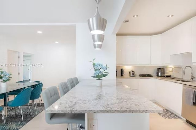 kitchen featuring light stone countertops, modern cabinets, a sink, white cabinetry, and stainless steel dishwasher