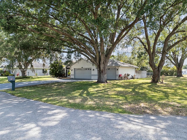 obstructed view of property featuring fence, driveway, and a front yard
