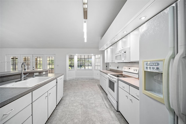 kitchen with white cabinetry, baseboards, white appliances, and a sink