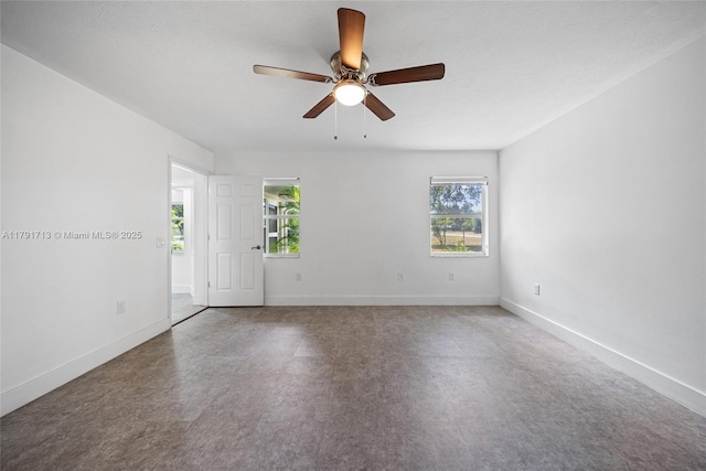 spare room with plenty of natural light, a ceiling fan, and baseboards