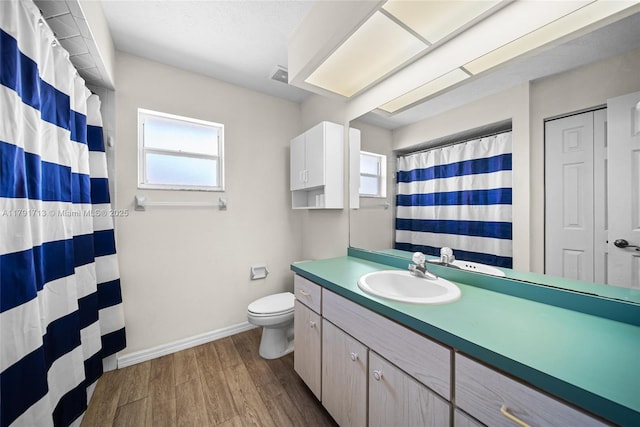 full bathroom with toilet, a wealth of natural light, wood finished floors, and baseboards