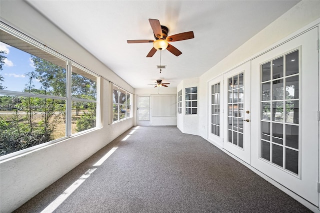 unfurnished sunroom featuring a ceiling fan, carpet flooring, and french doors