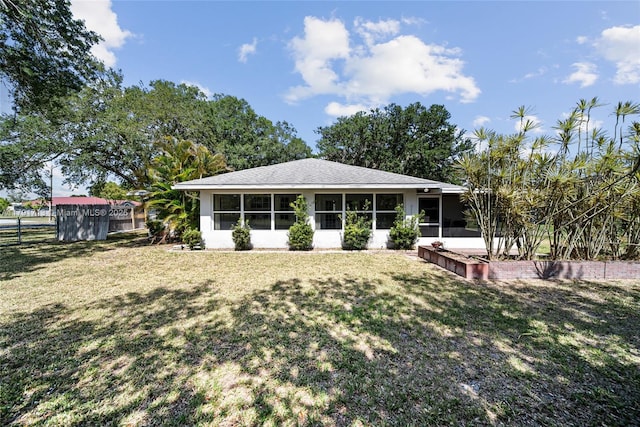 back of house with fence, stucco siding, a sunroom, and a lawn