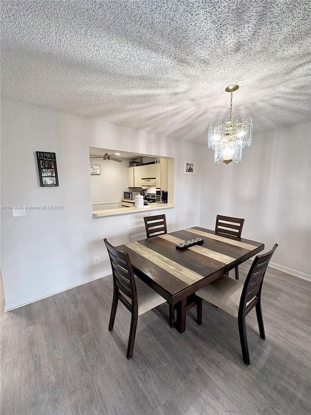 dining room featuring a textured ceiling, a chandelier, wood finished floors, and baseboards