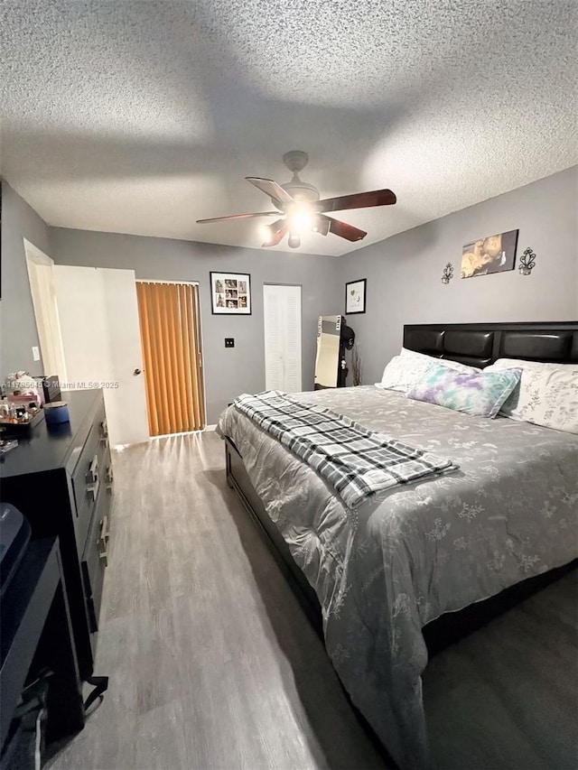 bedroom with a textured ceiling, wood finished floors, and ceiling fan