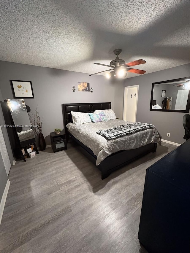 bedroom with baseboards, wood finished floors, ceiling fan, and a textured ceiling