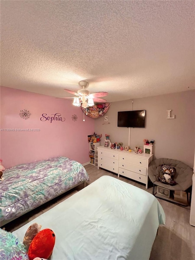 bedroom featuring light wood finished floors, a textured ceiling, and a ceiling fan
