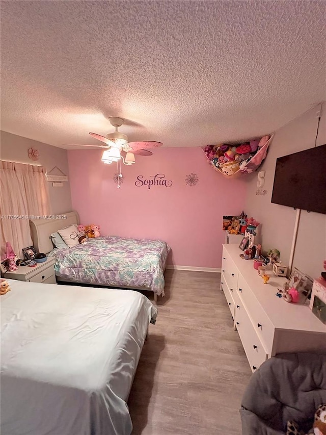 bedroom featuring a textured ceiling, a ceiling fan, and light wood-style floors