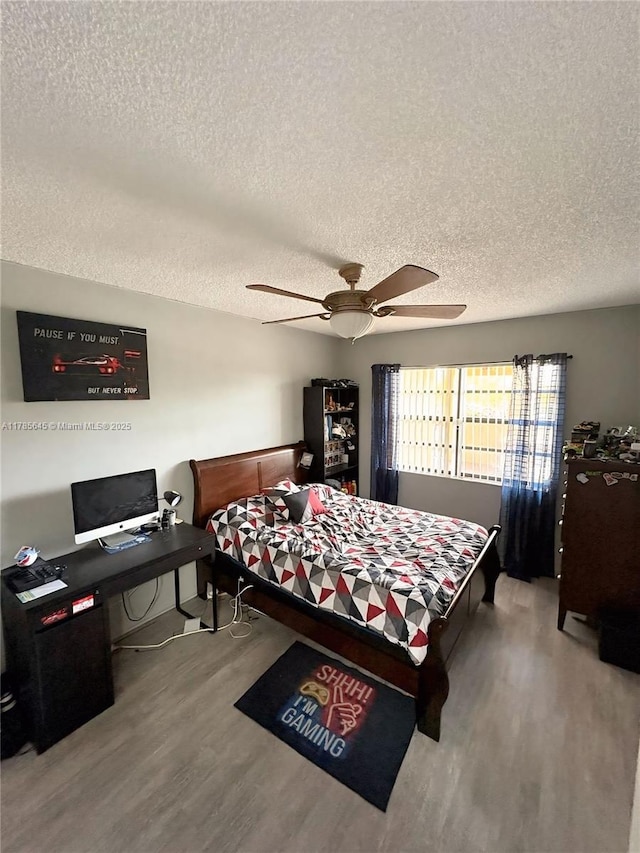 bedroom with wood finished floors, a ceiling fan, and a textured ceiling