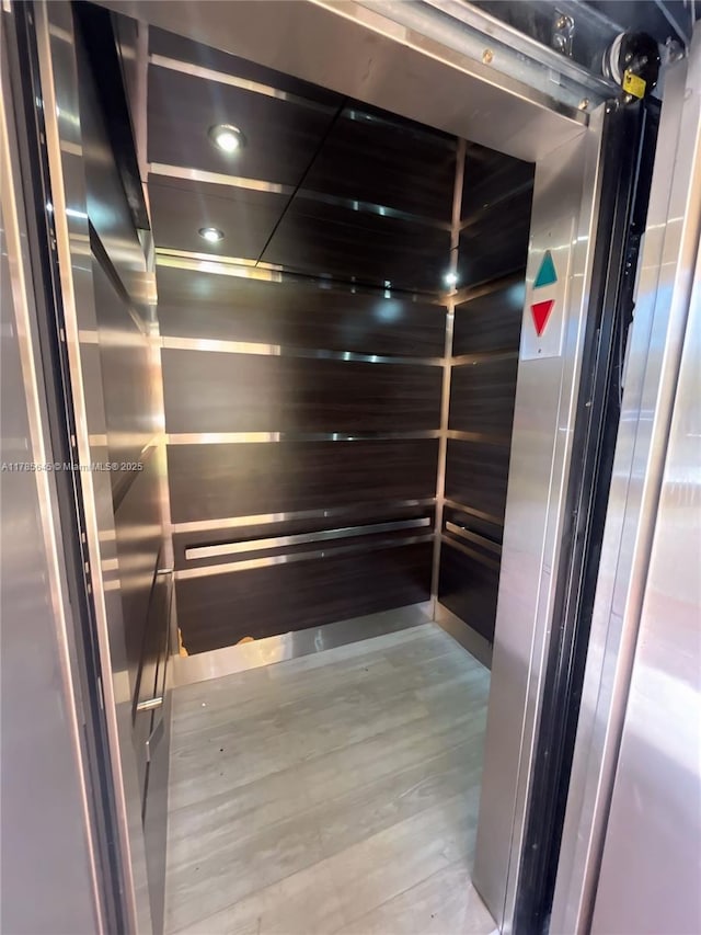 details with elevator, wood finished floors, and recessed lighting