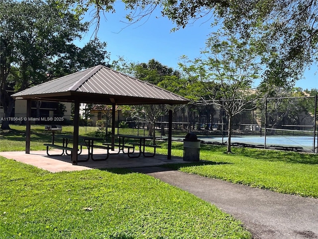 view of home's community with a lawn, a tennis court, a gazebo, and fence