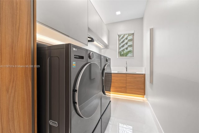clothes washing area featuring laundry area, independent washer and dryer, light tile patterned floors, a sink, and baseboards