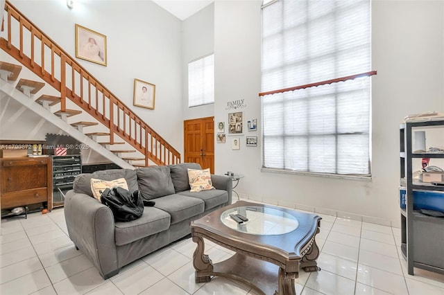living area featuring stairs, light tile patterned flooring, and a towering ceiling