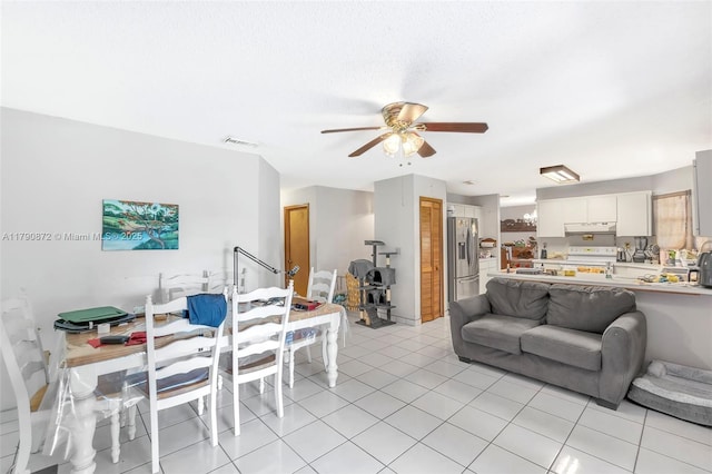 living area featuring light tile patterned floors, visible vents, and ceiling fan