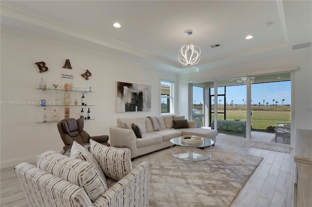 26047 SW Viterbo Way, Port St Lucie, FL 34986 - living room featuring light wood-style floors, visible vents, a raised ceiling, a notable chandelier, and crown molding