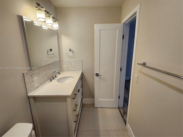 half bathroom with toilet, tile patterned floors, vanity, and baseboards