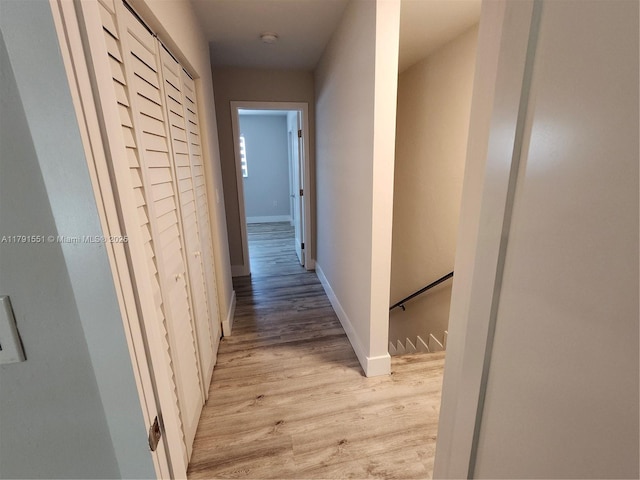 corridor featuring light wood-style flooring and baseboards
