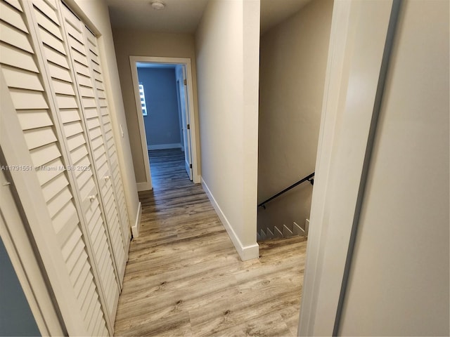 corridor with baseboards and light wood-type flooring