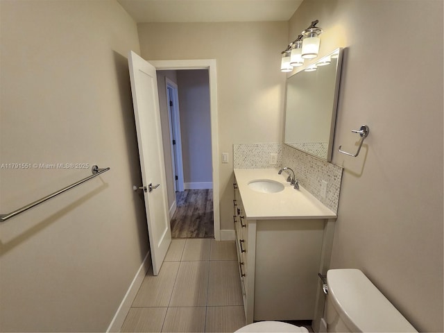 bathroom featuring vanity, tasteful backsplash, toilet, baseboards, and tile patterned flooring