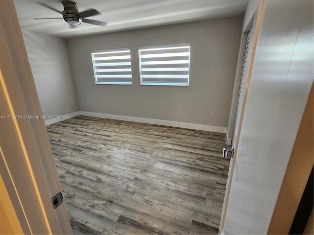 spare room with baseboards, wood finished floors, and a ceiling fan