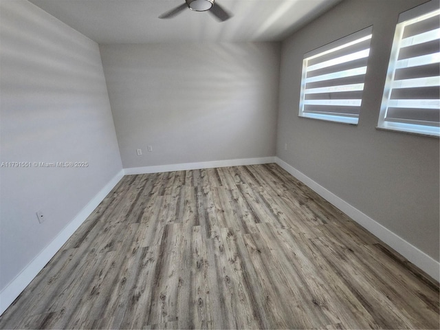 unfurnished room with baseboards, wood finished floors, and a ceiling fan