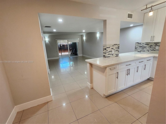 kitchen featuring white cabinetry, decorative backsplash, visible vents, light countertops, and baseboards