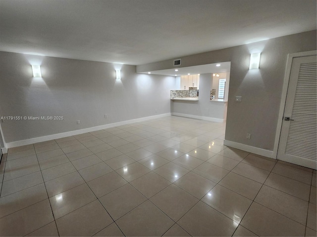 empty room with baseboards, visible vents, and light tile patterned floors