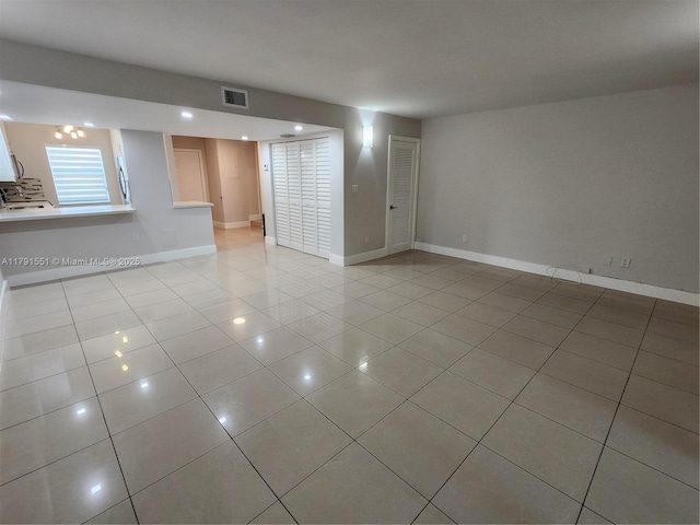 empty room featuring baseboards, visible vents, and light tile patterned floors