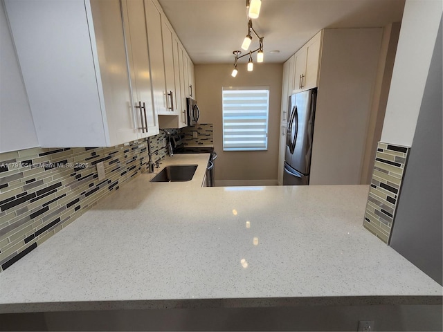 kitchen featuring backsplash, light stone countertops, a sink, and appliances with stainless steel finishes