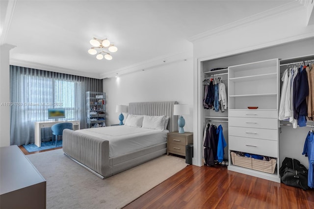 bedroom featuring wood finished floors, crown molding, and a closet