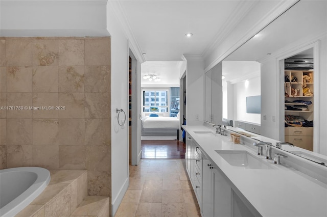 bathroom featuring crown molding, a sink, double vanity, a relaxing tiled tub, and ensuite bath