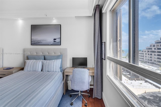 bedroom featuring wood finished floors, crown molding, and baseboards