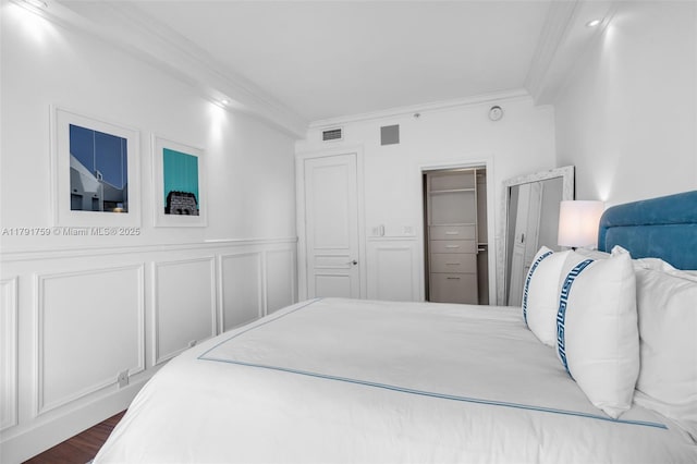 bedroom with visible vents, a wainscoted wall, ornamental molding, and a closet