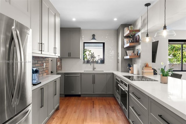 kitchen with a sink, decorative backsplash, light countertops, gray cabinetry, and appliances with stainless steel finishes