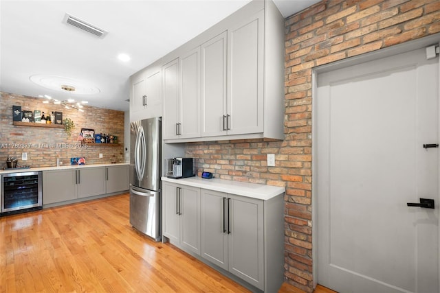 kitchen with beverage cooler, visible vents, gray cabinetry, and freestanding refrigerator