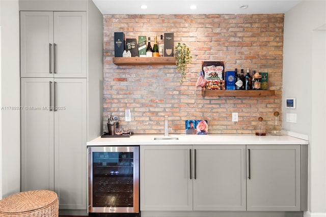 bar featuring recessed lighting, indoor wet bar, a sink, brick wall, and wine cooler