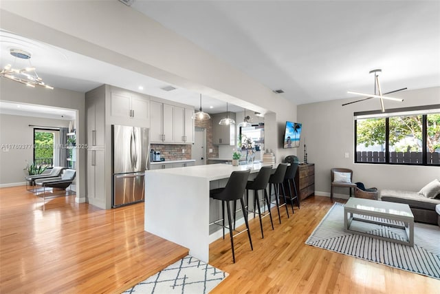kitchen featuring light wood-style flooring, a healthy amount of sunlight, freestanding refrigerator, and light countertops