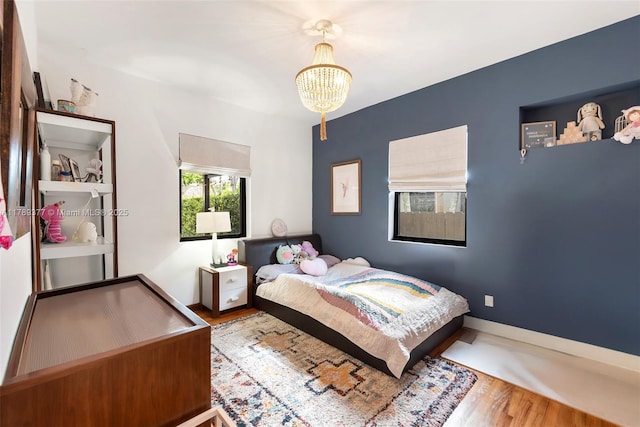 bedroom with an inviting chandelier, wood finished floors, and baseboards