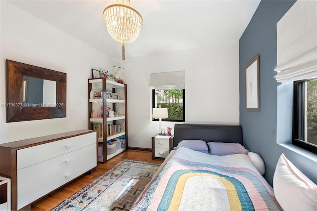 bedroom with multiple windows, wood finished floors, and a chandelier