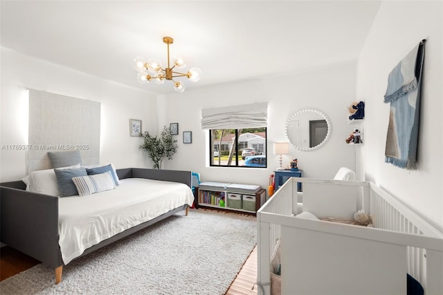 bedroom featuring an inviting chandelier and wood finished floors