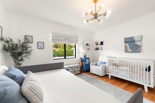 bedroom featuring an inviting chandelier and wood finished floors