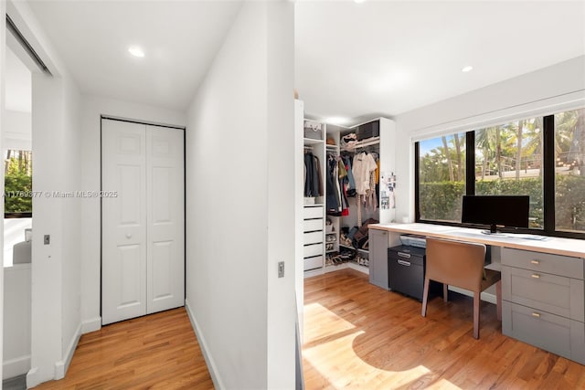 walk in closet featuring light wood-type flooring and built in desk