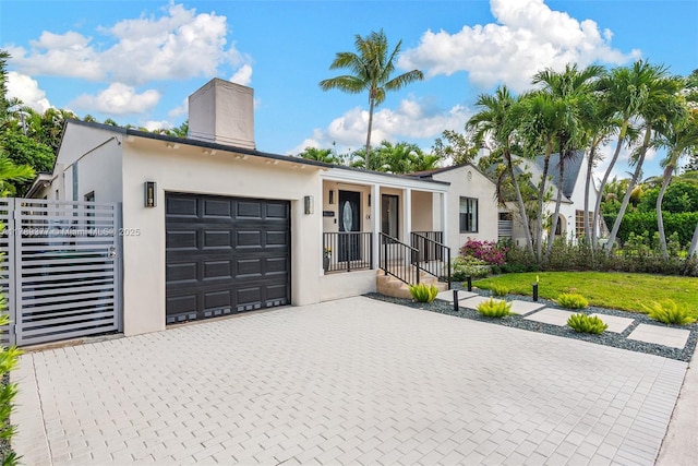 modern home featuring a front lawn, decorative driveway, an attached garage, and stucco siding
