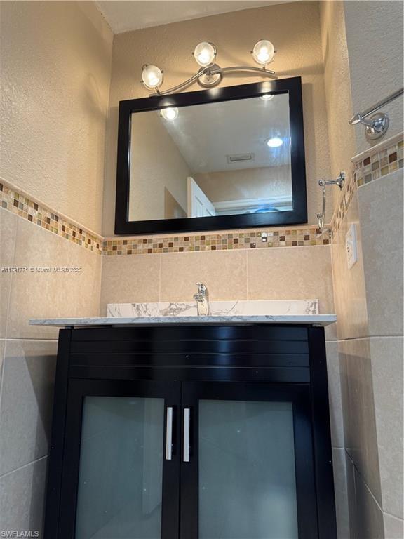1127 Foggia St E, Lehigh Acres, FL 33974 - bathroom with tile walls, a textured wall, and vanity
