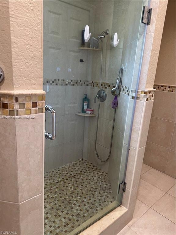 1127 Foggia St E, Lehigh Acres, FL 33974 - bathroom with a stall shower, tile walls, a textured wall, and tile patterned floors