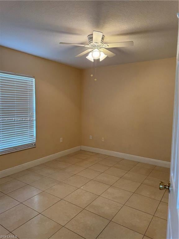 1127 Foggia St E, Lehigh Acres, FL 33974 - unfurnished room with light tile patterned flooring, ceiling fan, baseboards, and a textured ceiling