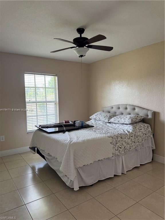1127 Foggia St E, Lehigh Acres, FL 33974 - bedroom with baseboards, light tile patterned floors, and a ceiling fan