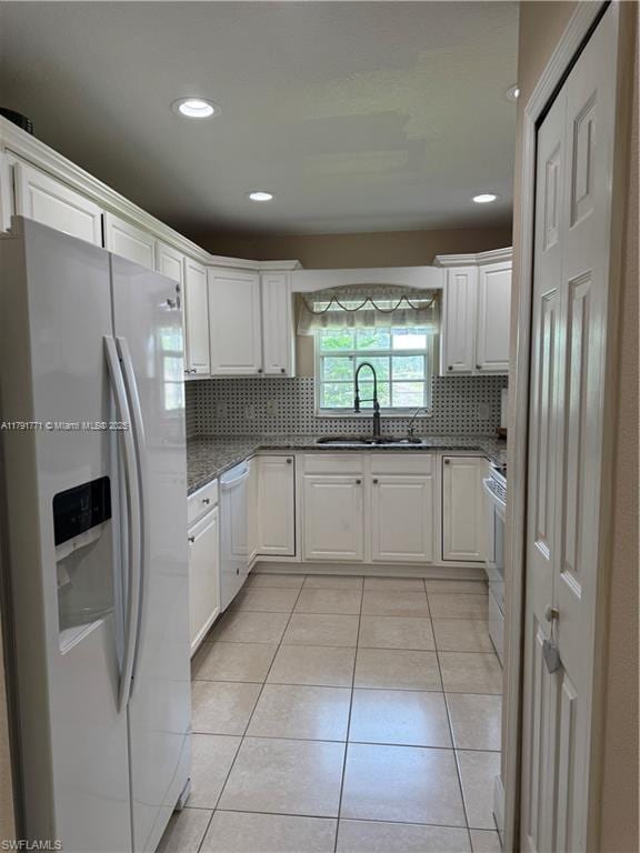 1127 Foggia St E, Lehigh Acres, FL 33974 - kitchen featuring light tile patterned floors, white cabinets, a sink, white appliances, and backsplash