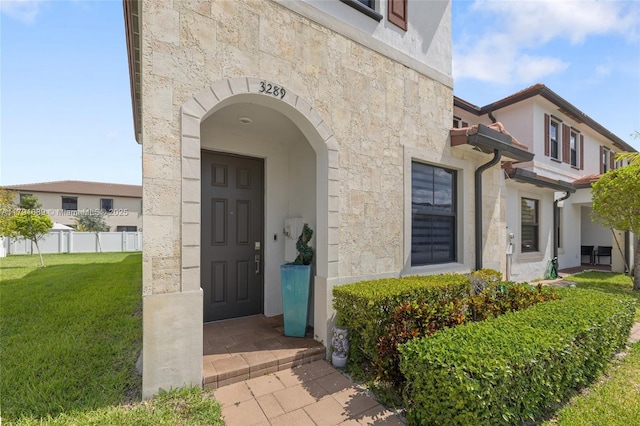 3289 W 106th Ter, Hialeah, FL 33018 - doorway to property featuring a lawn, fence, stucco siding, and stone siding