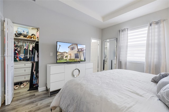 3289 W 106th Ter, Hialeah, FL 33018 - bedroom featuring light wood-style floors, a closet, baseboards, a spacious closet, and a tray ceiling